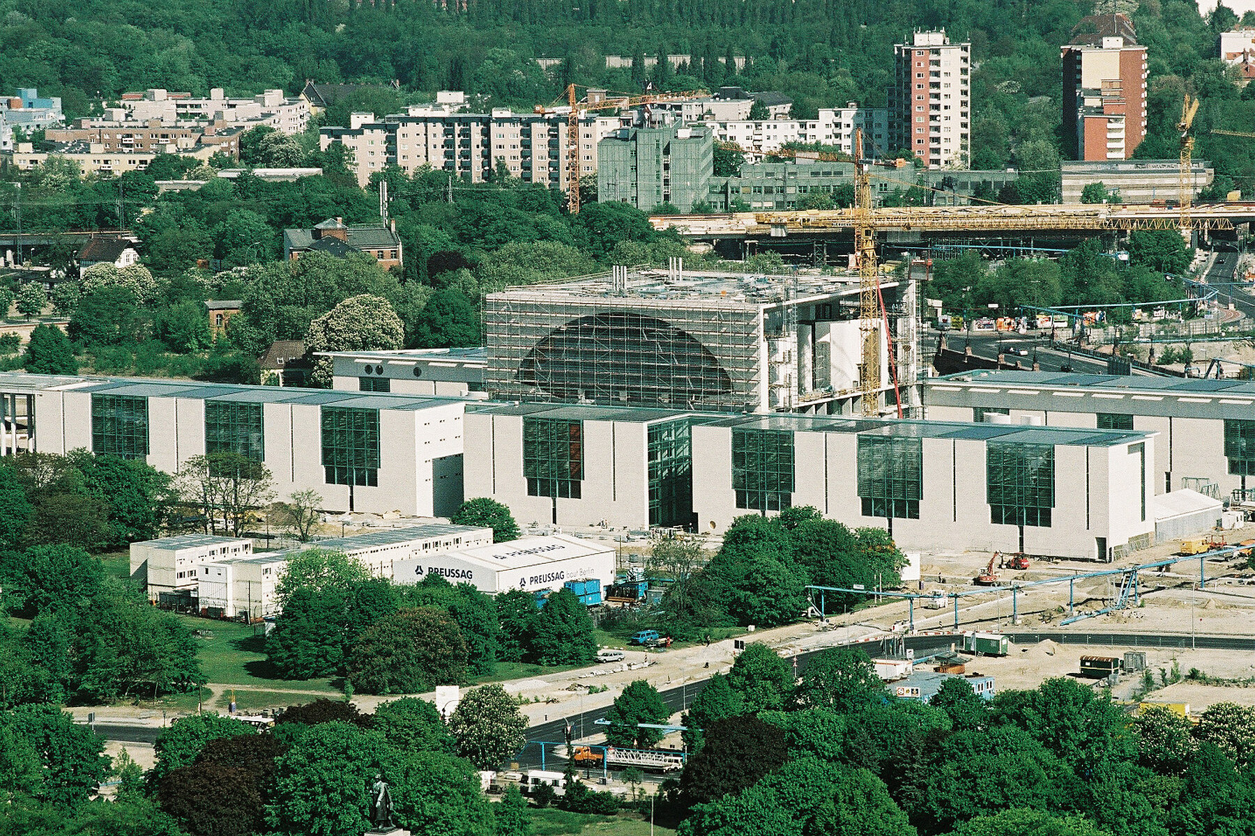 The Federal Chancellery under construction in Berlin's government district. The main wing of the building is scaffolded, a crane stands next to it.