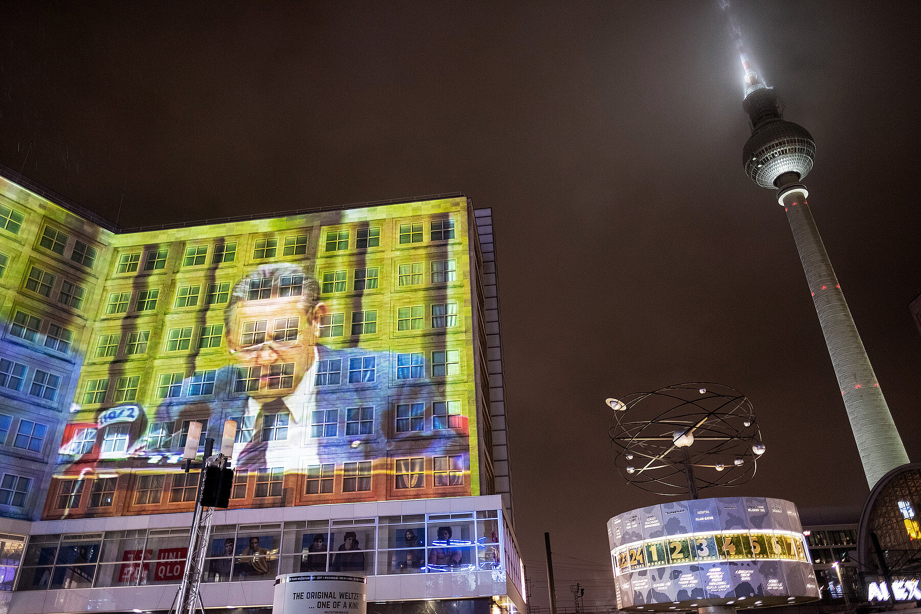 Nächtliche Projektion von Günter Schabwoksi auf ein Gebäude am Alexanderplatz. Links im Bild die Weltzeituhr und der Fernsehturm.