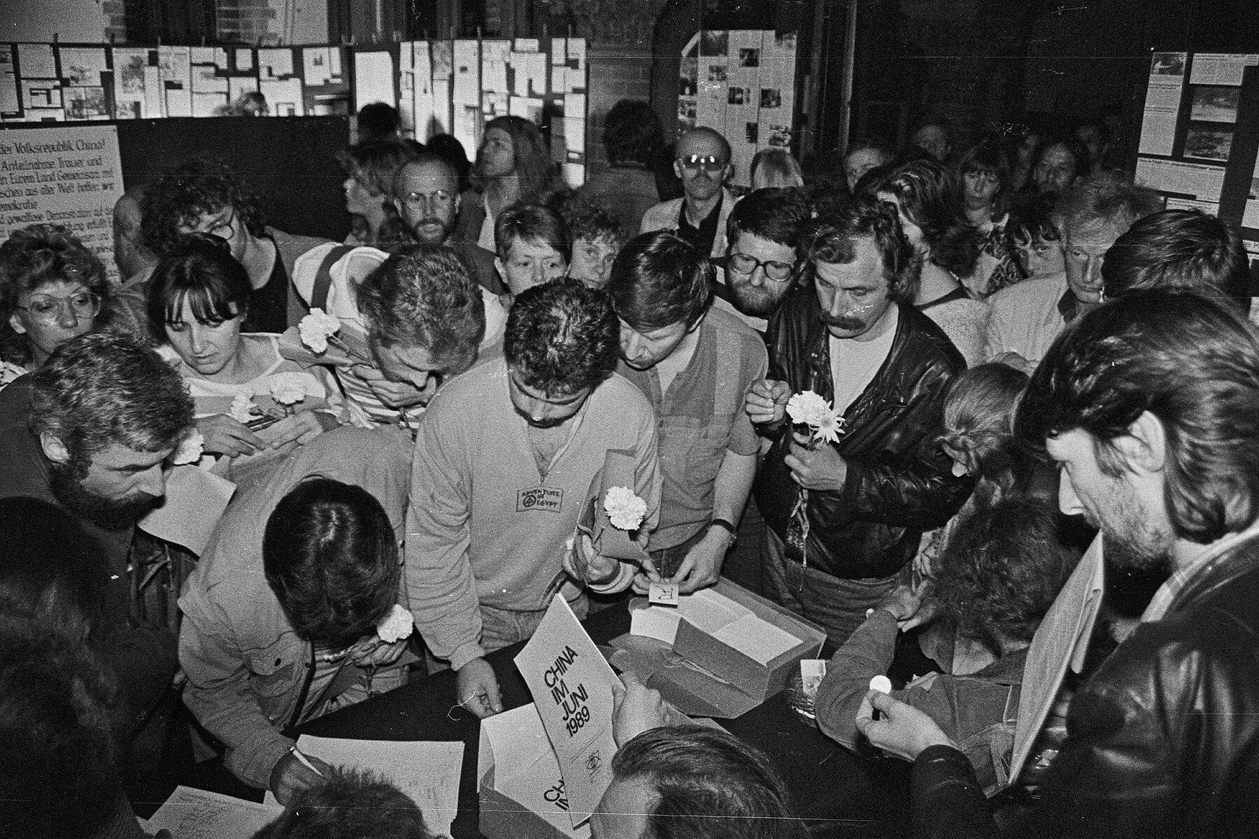 People in the Samariterkirche held white carnations in their hands and looked at information material spread out on a table.