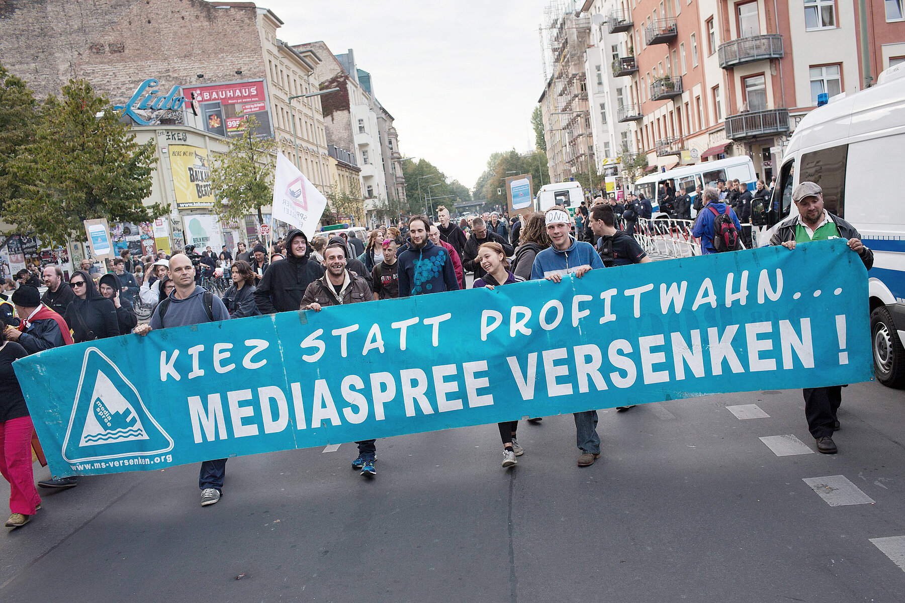 Demonstrationszug mit einem großen blauen Transparent, auf dem mit weißer Aufschrift steht: Kiez statt Profitwahn. Mediaspree versenken."