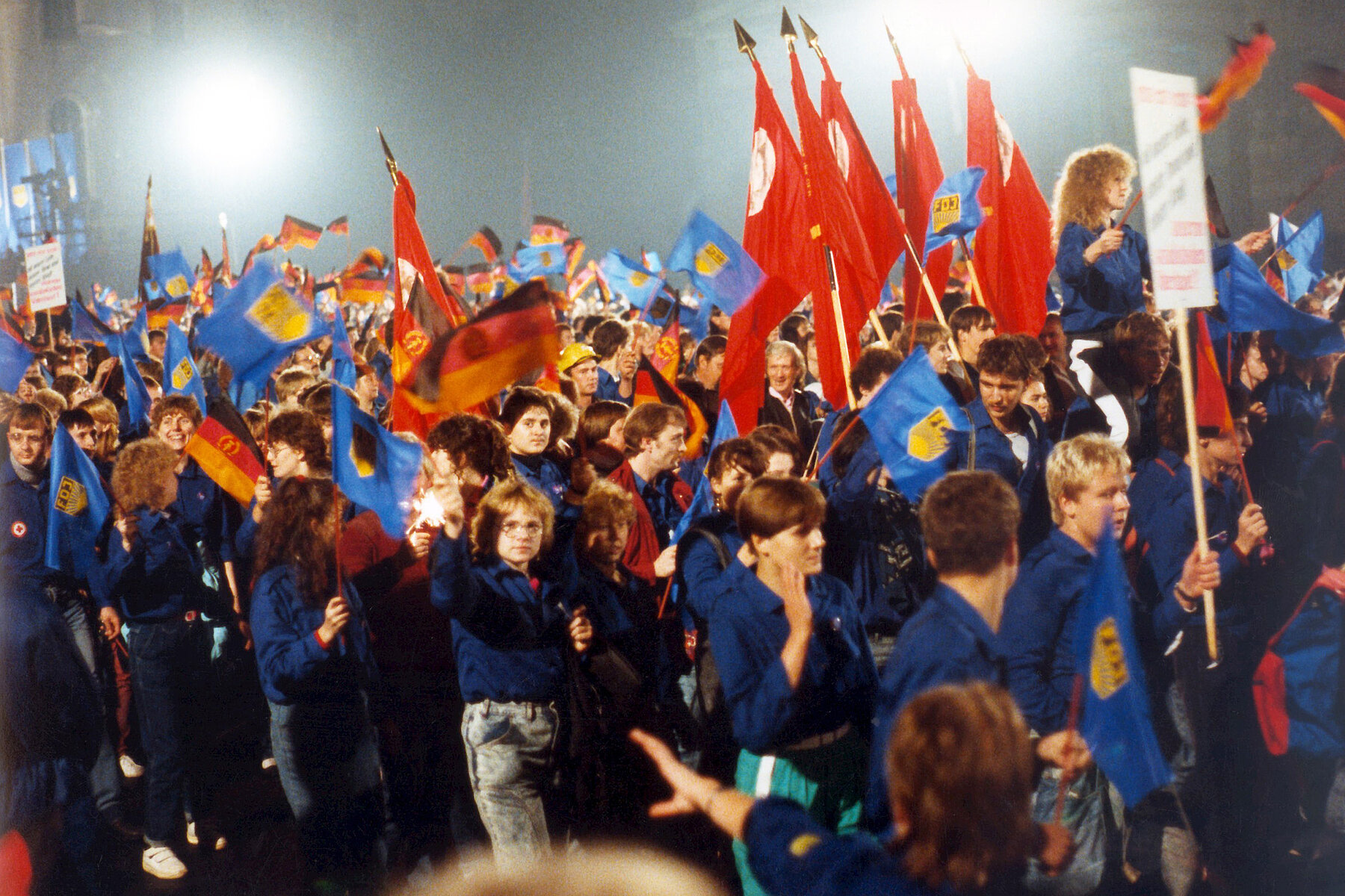 On the 40th anniversary of the GDR, members of the Free German Youth march in blue shirts and with red flags on the street Unter den Linden.