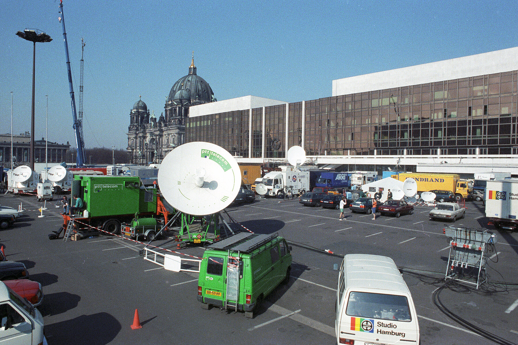 Übertragungswagen mit Satellitenschüsseln stehen auf einem Parkplatz vor dem Palast der Republik. Links hinten befindet sich der Berliner Dom.
