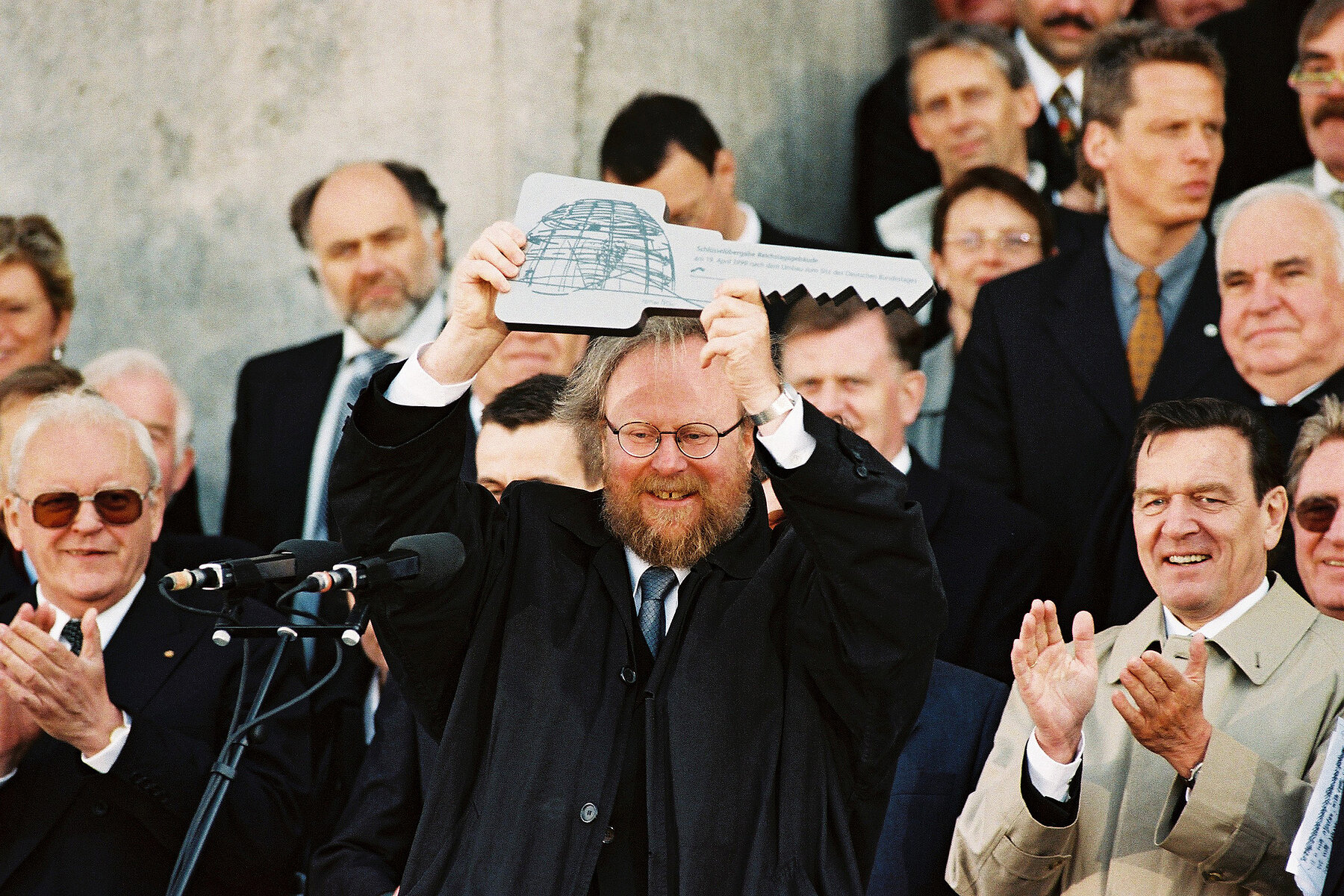 Wolfgang Thierse in der Bildmitte hält einen übergroßen Schlüssel. Er ist umgeben von weiteren Politikern wie Helmut Kohl und Gerhard Schröder. 