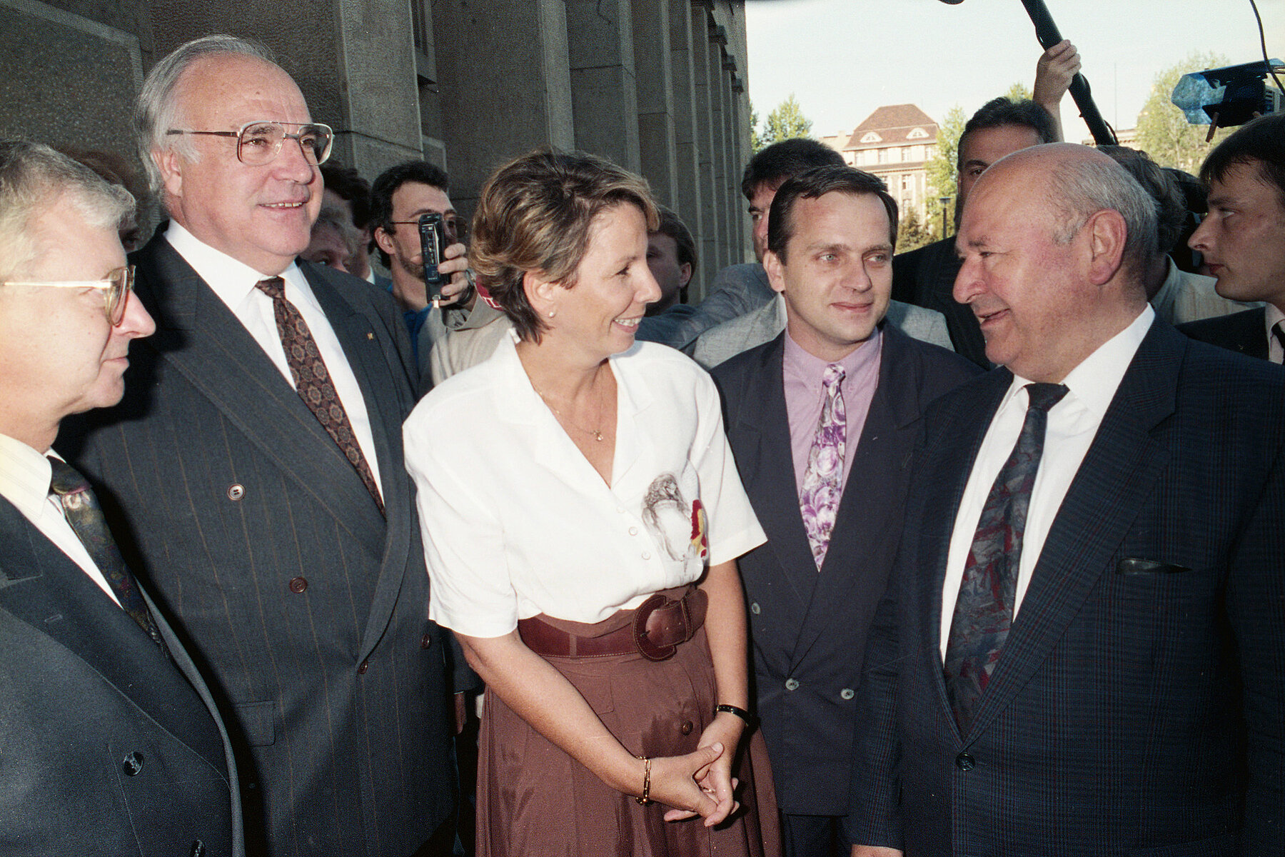 DDR-Parlamentspräsidentin Sabine Bergmann-Pohl steht in weißer Bluse und braunem Rock in der Mitte von vier Bonner Spitzenpolitikern im Anzug, links von ihr steht Bundeskanzler Helmut Kohl.  