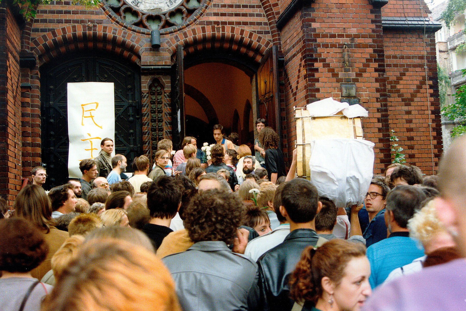 A crowd of people gather in front of the Samariterkirche.