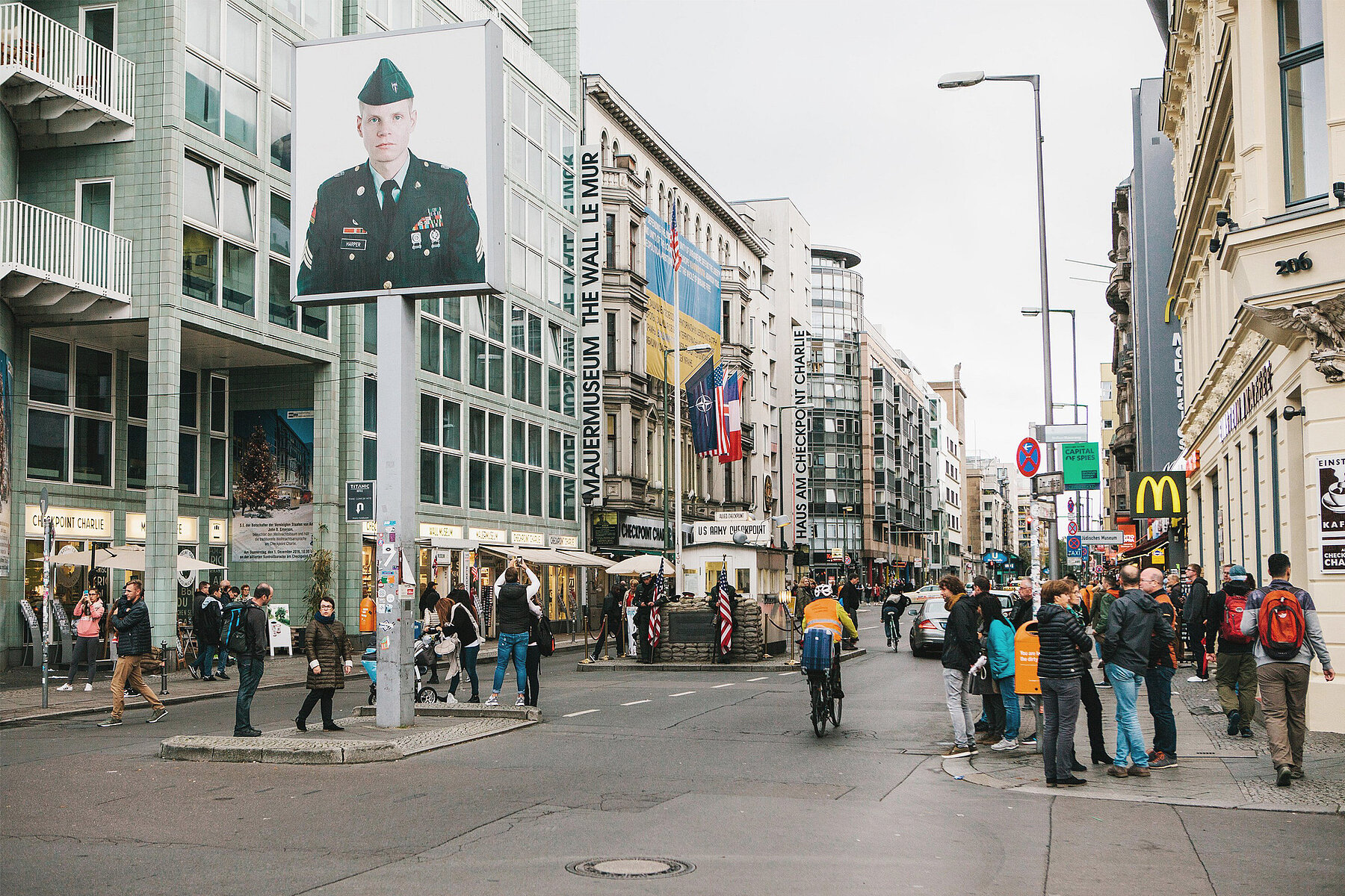 In the foreground is a large photograph of a U.S. soldier, in the background is the Allied control booth. On the left, the Mauermuseum.