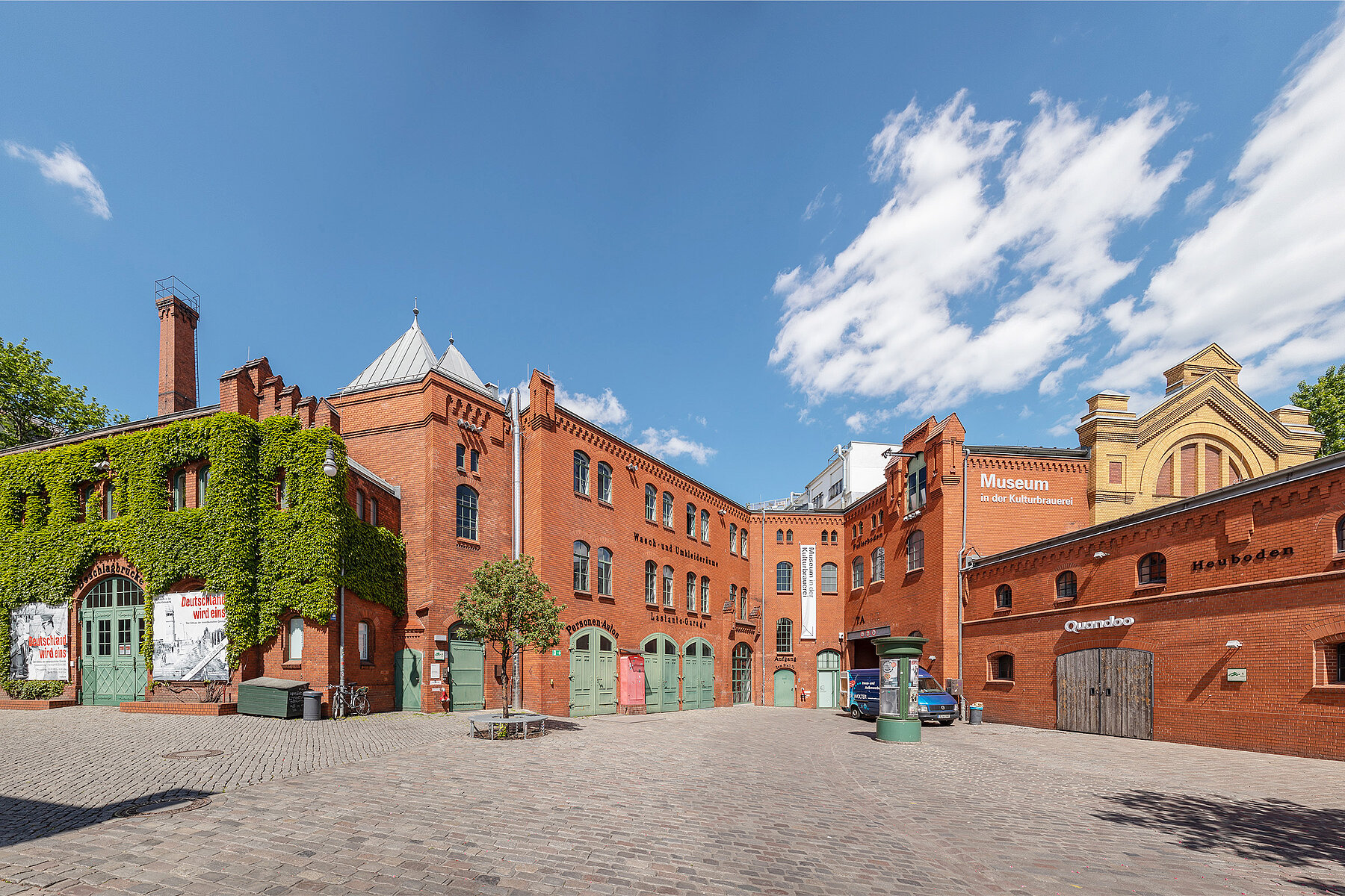 Inner courtyard of the red-brick Kulturbrauerei. Shown is the corner of the museum in the Kulturbrauerei with green doors and windows.
