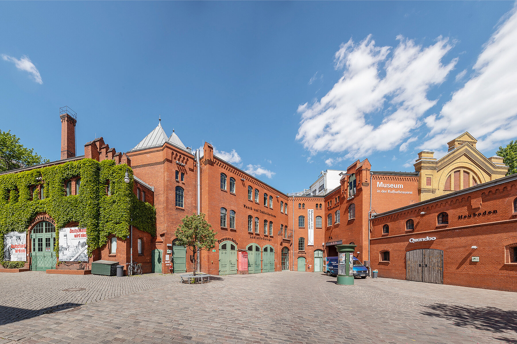 Innenhof der rotgeklinkerten Kulturbrauerei. Dargestellt ist die Ecke des Museums in der Kulturbrauerei mit grünen Türen und Fenstern.