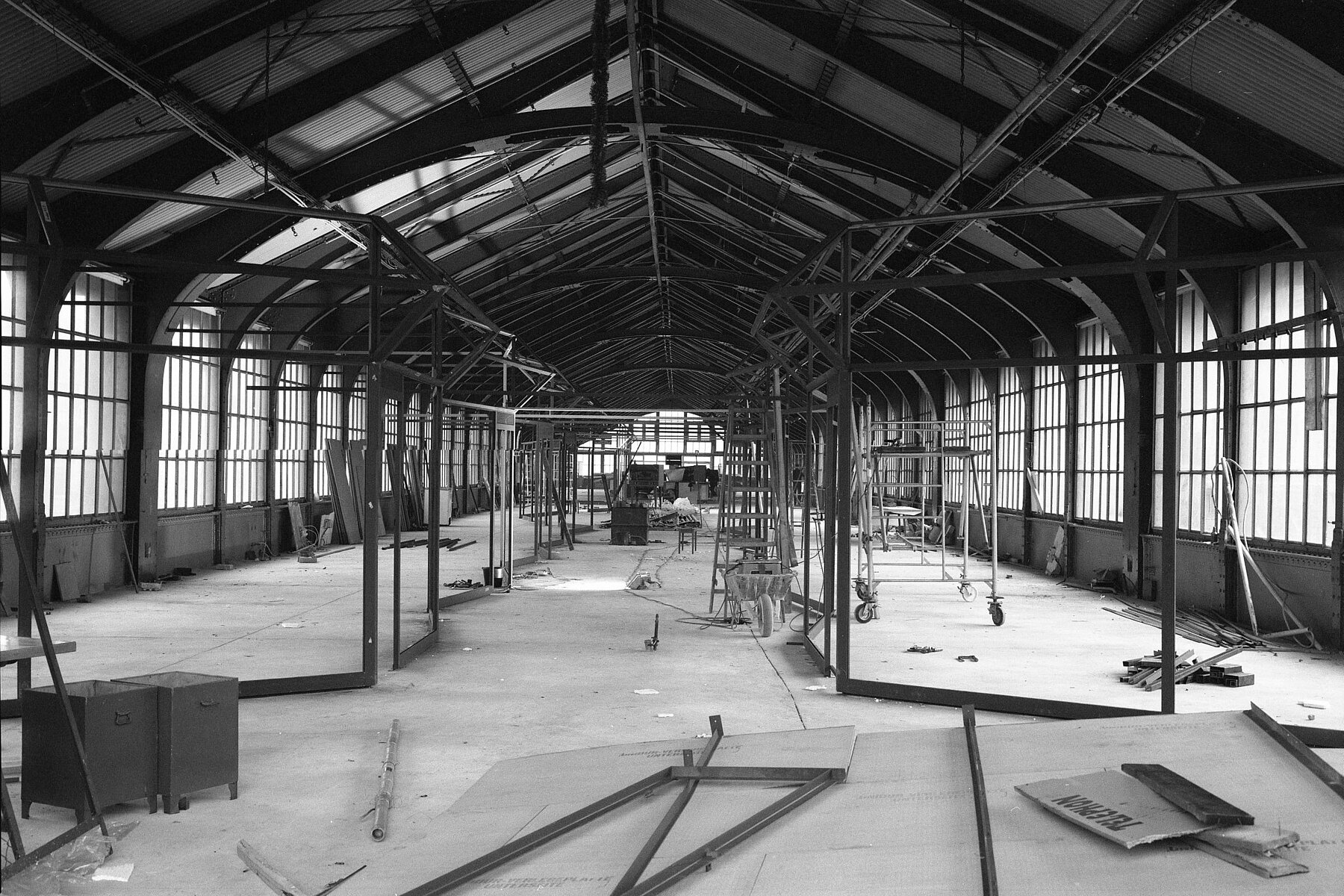 Inside the building of the elevated station, the tracks are being built over. On the left and right are scaffolds, and there are wooden boards on the floor. 