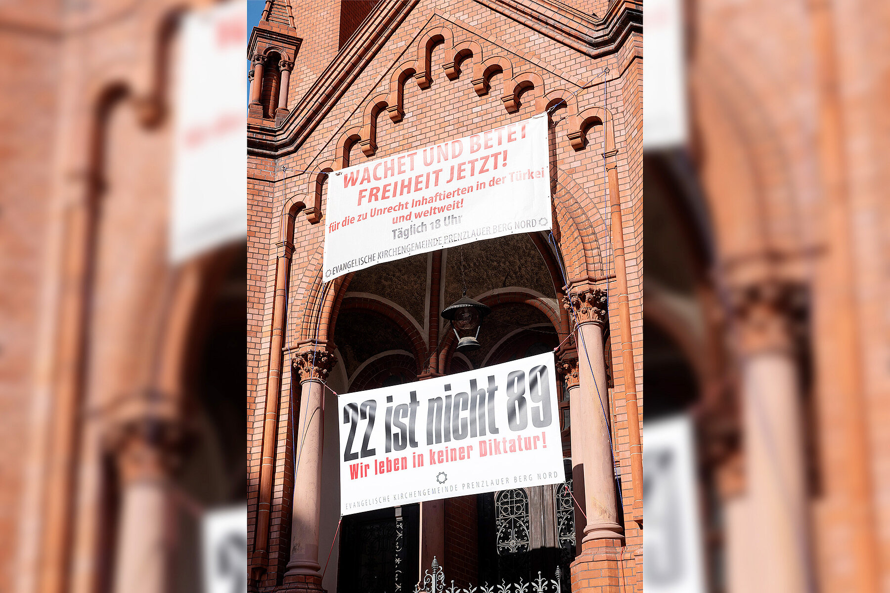 Zwei Banner mit Aufschriften hängen am Eingangstor der Kirche. 