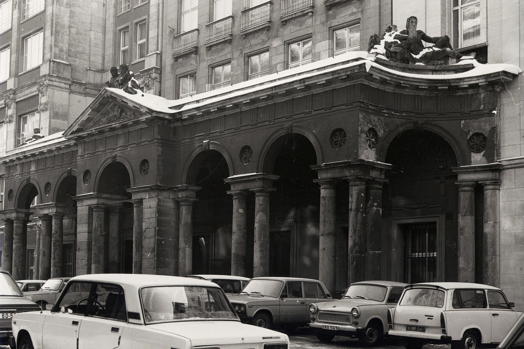 Entrance area with columns. Parked Trabants and Ladas stand in front of it.