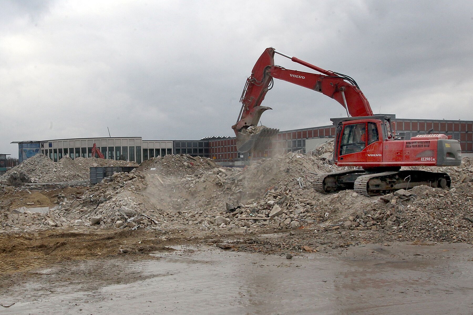 A red bulldozer digs up crushed rubble.