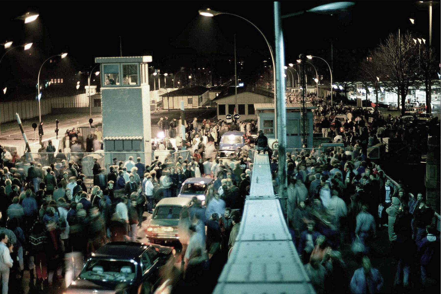 Crowds of people and cars cross the border at the Bösebrücke on Bornholmer Straße.