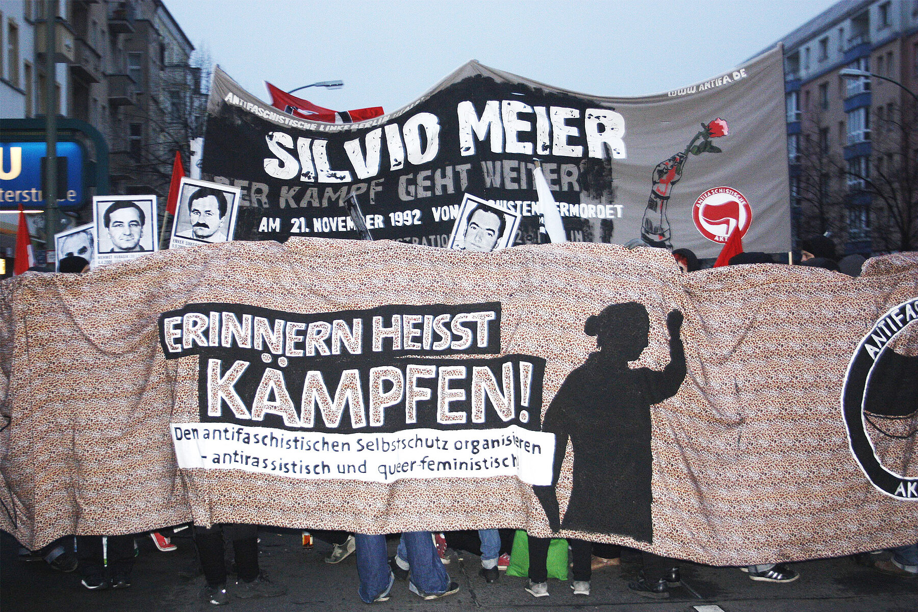 A banner on a demonstration. In the foreground with the inscription Remembering Means Fighting. In the background with the inscription Silvio Meier. The Fight Continues. 