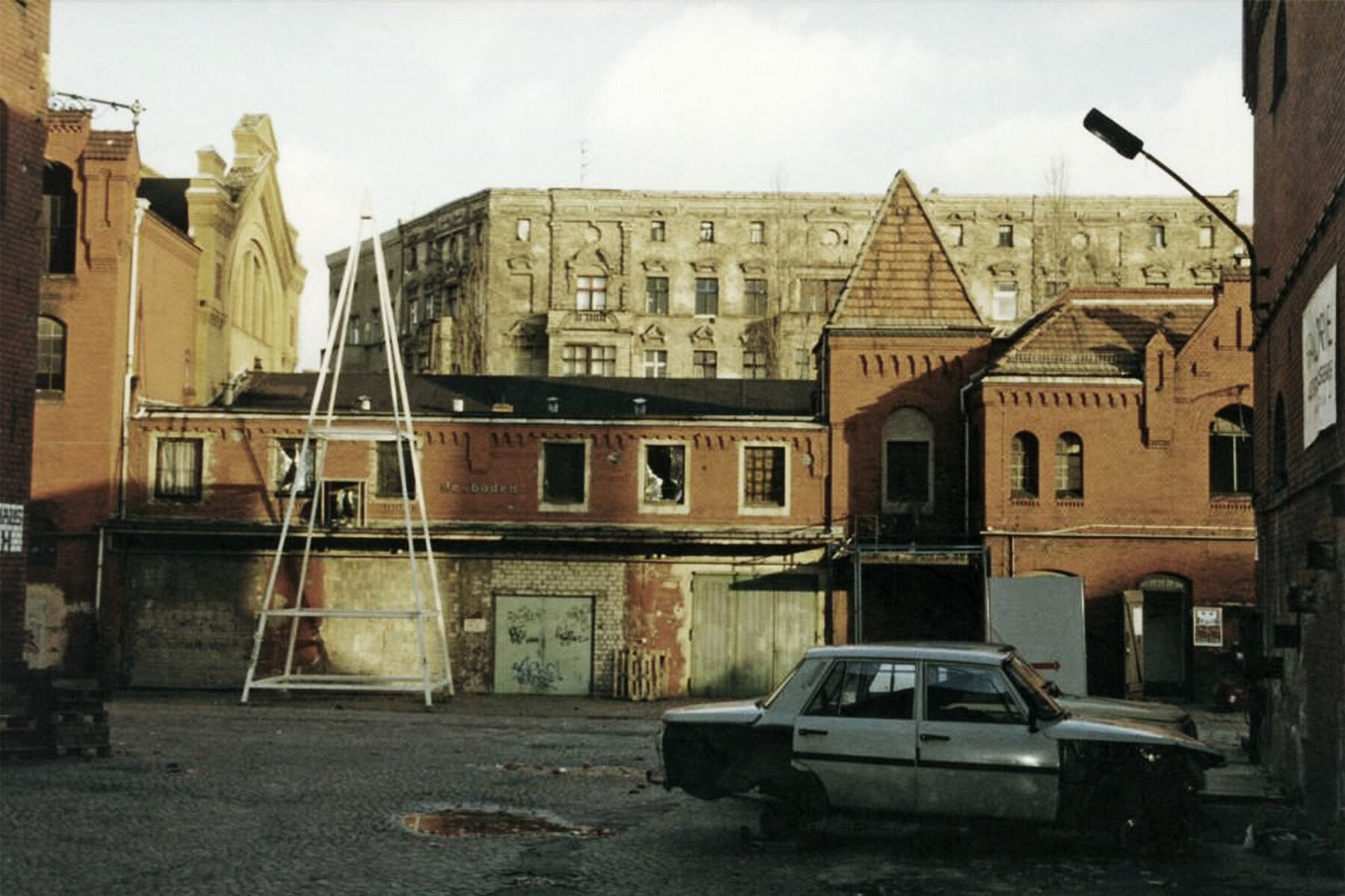 Dilapidated brewery premises from the courtyard. On the right is a broken car without tyres.