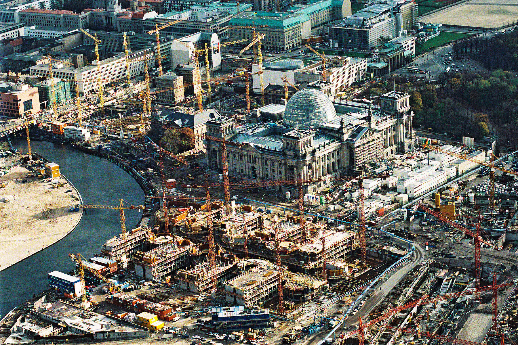 An aerial perspective of the construction site surrounding the Reichstag building. On the left is the Spree.